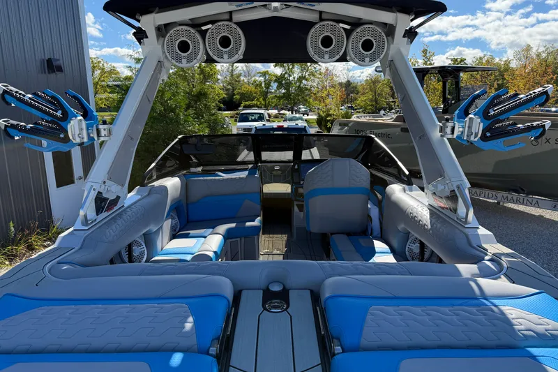 Slide: The Image of 2025 Centurion Ri230 boat interior with blue and gray seating, advanced sound system, and wakeboard racks. - 5