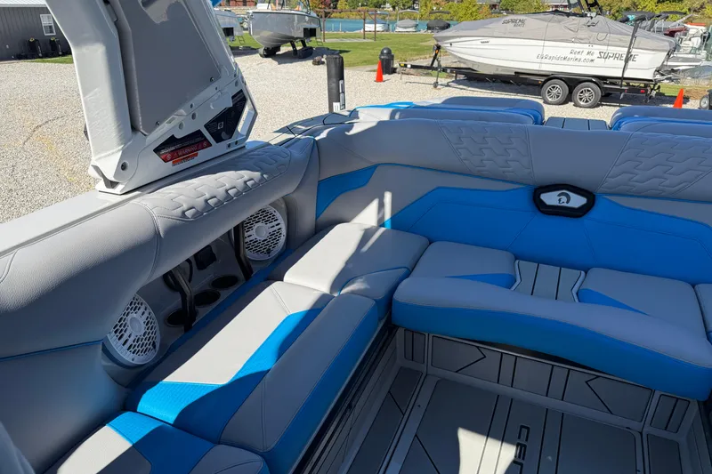 Slide: The Image of 2025 Centurion Ri230 boat interior with blue and gray seating, speakers, and storage compartments. - 9
