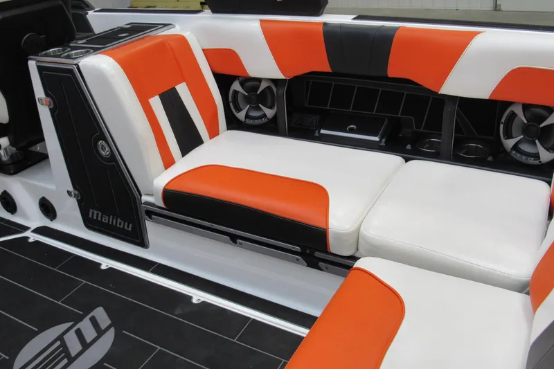 Slide: The Image of 2021 Malibu Wakesetter 24 MXZ interior with orange and white seating, featuring built-in speakers. - 7