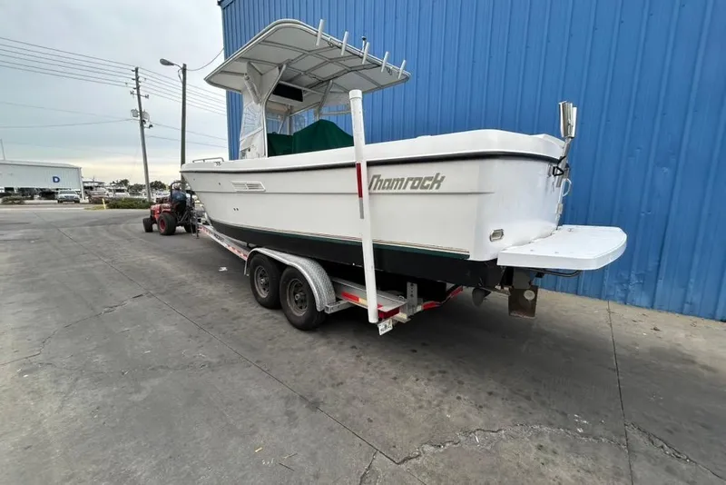 Slide: The Image of 2002 Shamrock 270 Open boat on trailer, parked near blue building. - 6