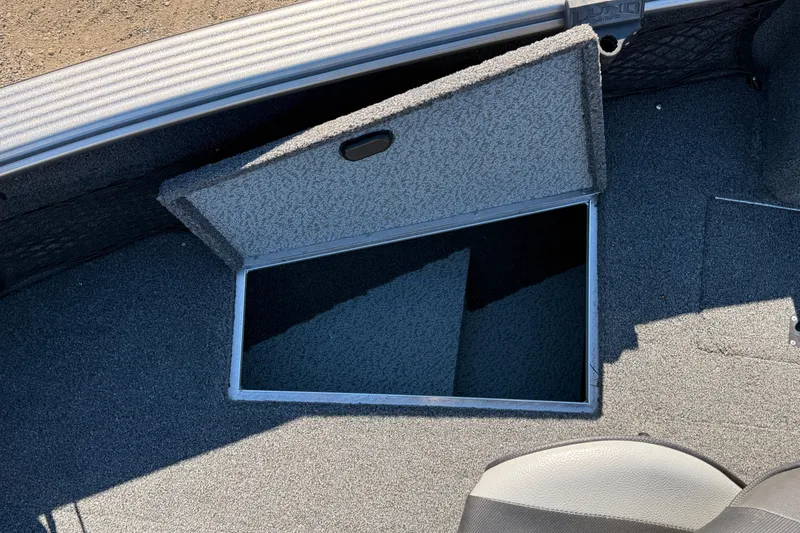 Slide: The Image of 2019 Lund 2025 Impact XS boat storage compartment with open hatch, gray carpet interior. - 10