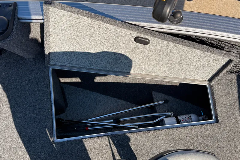 Slide: The Image of Open storage compartment in 2019 Lund 2025 Impact XS boat, containing metal rods and a fire extinguisher. - 12