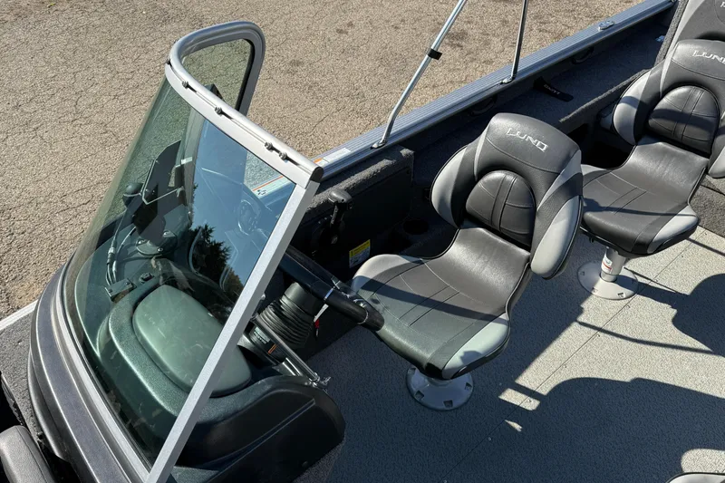 Slide: The Image of 2019 Lund 2025 Impact XS boat interior with steering console and two cushioned seats. - 19