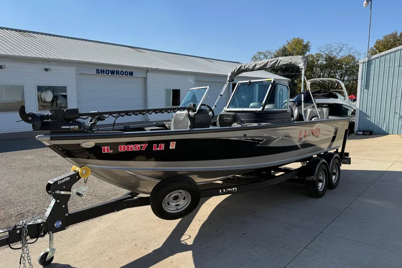 Slide: The Image of 2019 Lund 2025 Impact XS boat on trailer outside showroom. - 2
