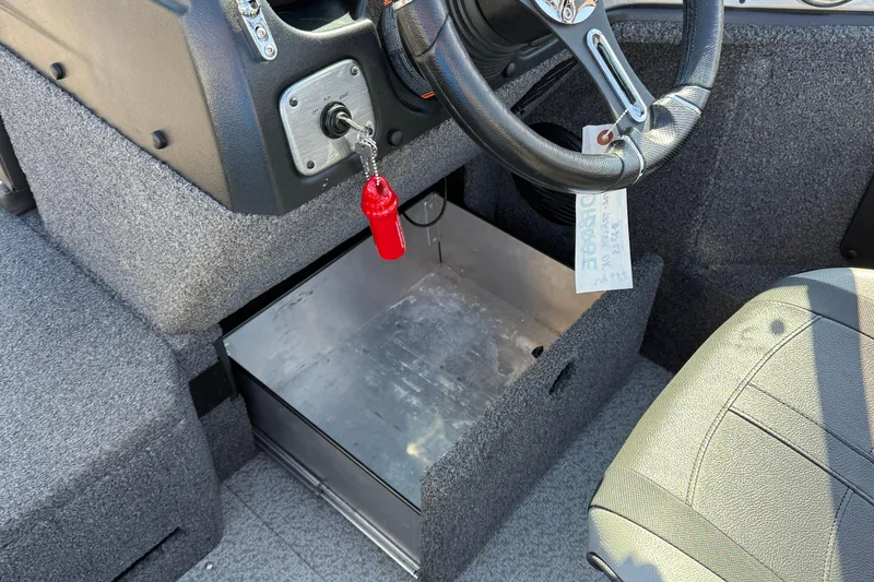 Slide: The Image of 2019 Lund 2025 Impact XS boat interior with steering wheel and storage compartment. - 24