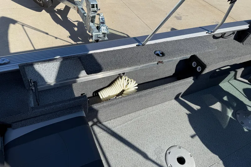 Slide: The Image of 2019 Lund 2025 Impact XS boat interior with storage compartment and coiled hose. - 30