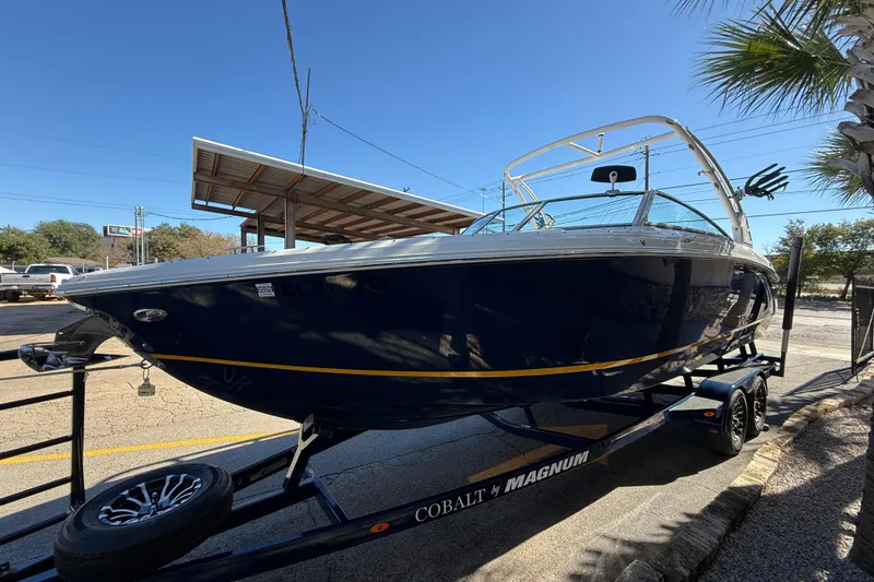 Slide: The Image of 2018 Cobalt R7 Surf boat on trailer, parked outdoors under clear blue sky. - 4