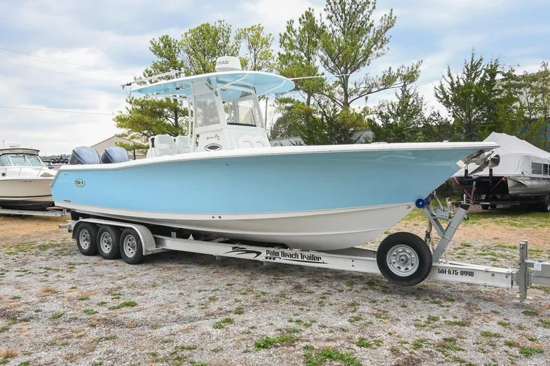 The Image of 2015 Sea Hunt Gamefish 30 boat on trailer, light blue hull, parked outdoors. - 0