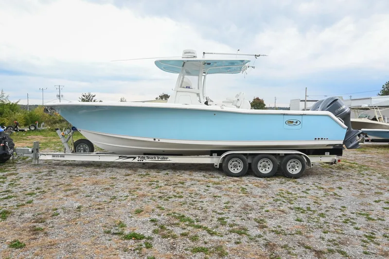 Slide: The Image of 2015 Sea Hunt Gamefish 30 boat on trailer, light blue hull, parked outdoors. - 2