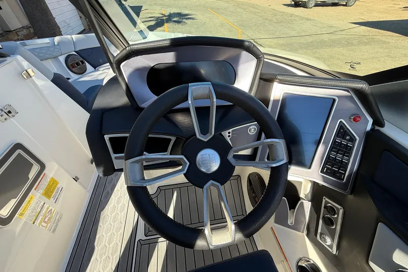 Slide: The Image of 2023 MasterCraft XT23 boat dashboard with modern steering wheel and touchscreen controls. - 11