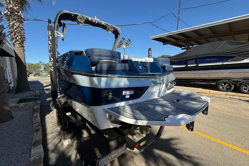 Slide: The Image of 2023 MasterCraft XT23 boat with sleek design, parked outdoors under clear blue sky. - 4