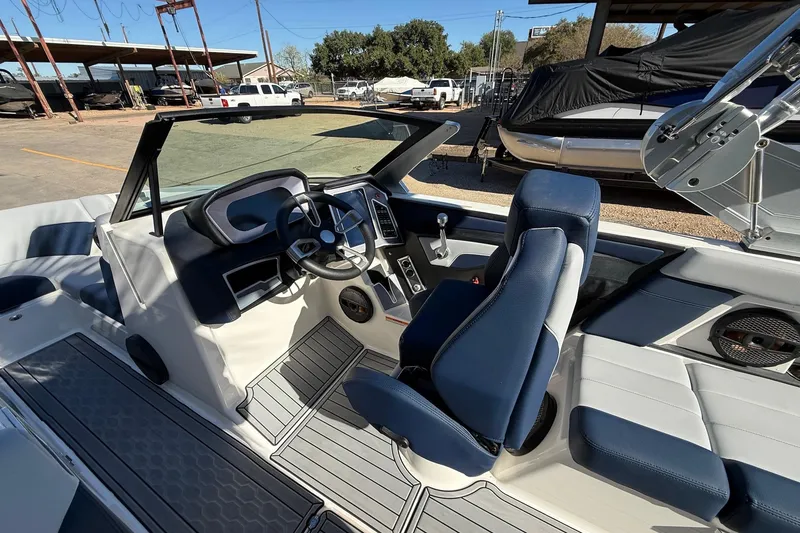 Slide: The Image of 2023 MasterCraft XT23 boat interior with blue and white seating, steering wheel, and dashboard. - 9