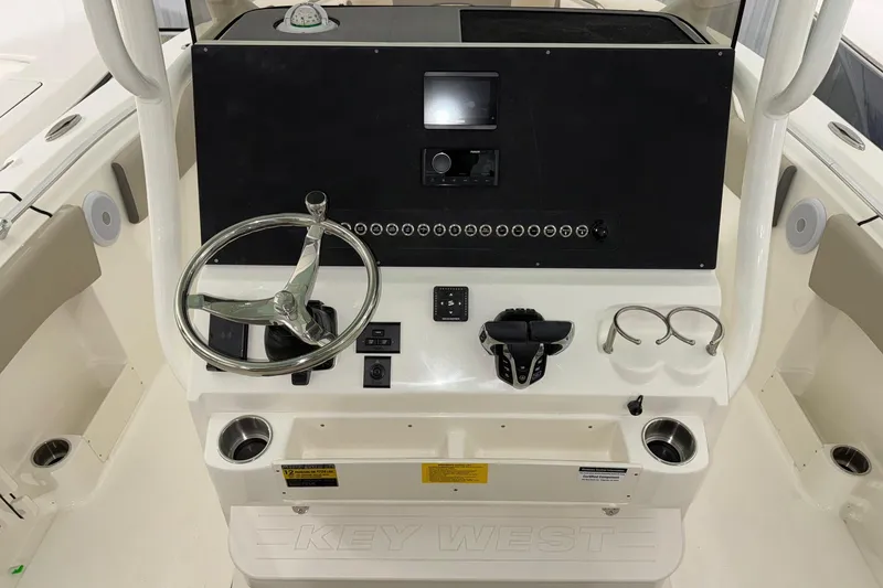 Slide: The Image of 2025 Key West 263 FS boat console with steering wheel, controls, and cup holders. - 14