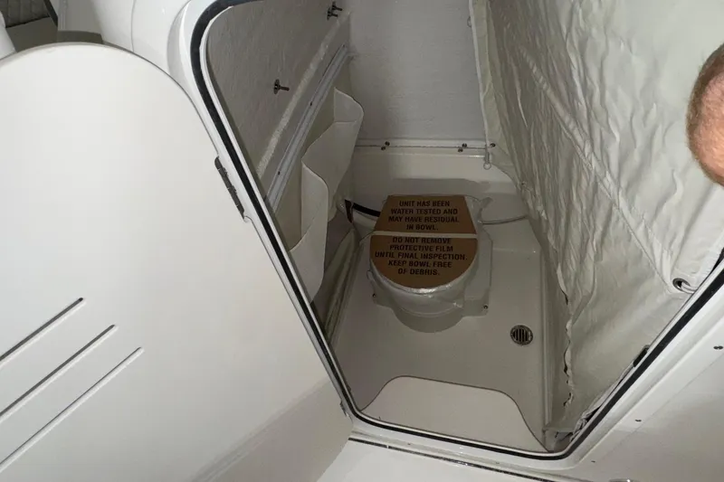 Slide: The Image of Interior of 2025 Key West 263 FS boat showing compact bathroom with protective film. - 17