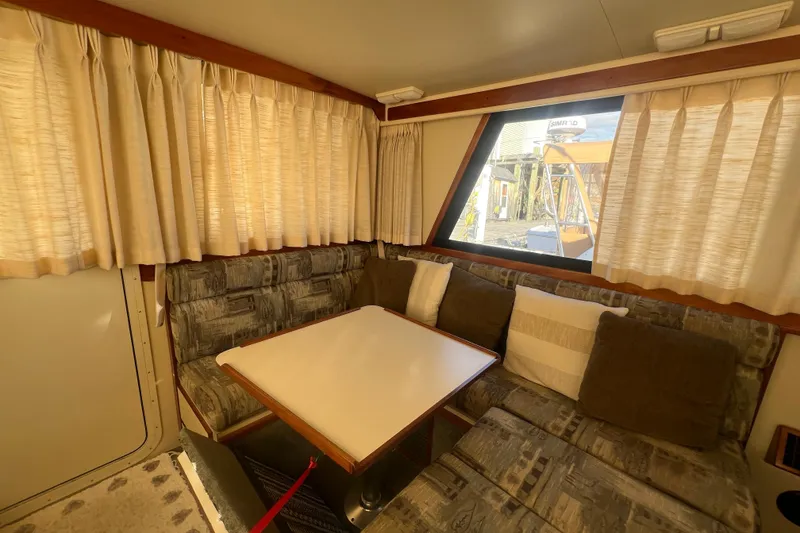 Slide: The Image of 2005 Camano Trawler interior with cozy seating and dining area, featuring curtains and cushions. - 12