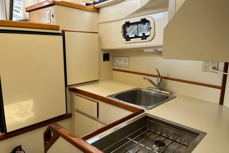 Slide: The Image of 2005 Camano Trawler kitchen with sink, stove, and storage cabinets. - 16