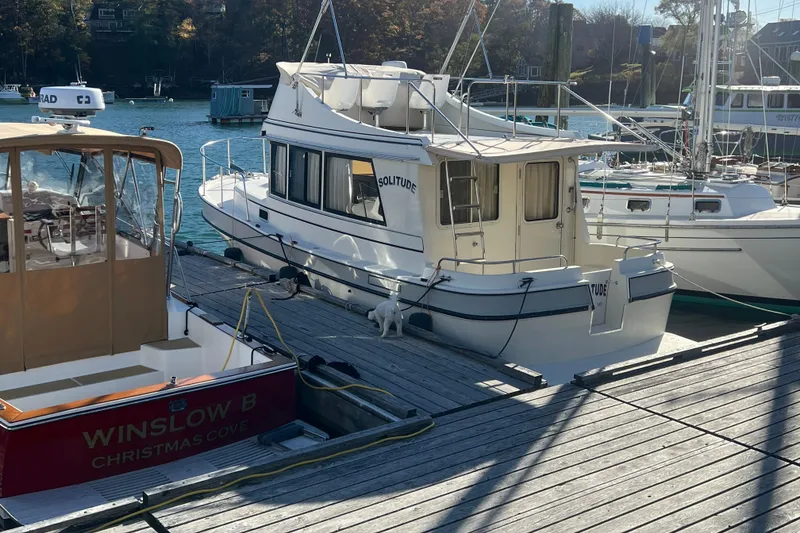 Slide: The Image of 2005 Camano Trawler docked at marina, surrounded by other boats, under clear skies. - 41