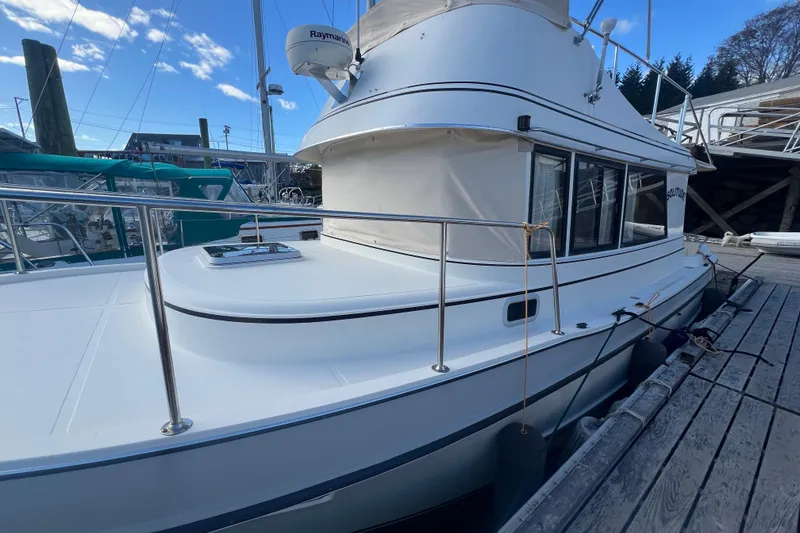 Slide: The Image of 2005 Camano Trawler docked, showcasing sleek design and spacious deck. - 5