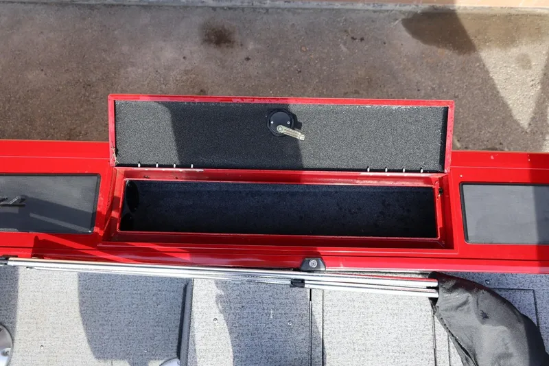 Slide: The Image of Open storage compartment on 2022 Tracker Targa V-19 WT boat, featuring red and gray interior. - 12