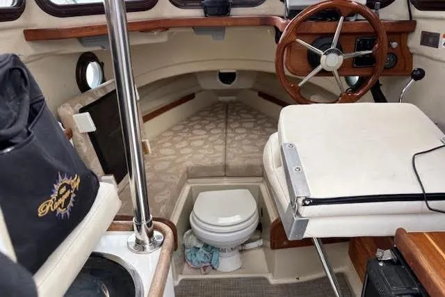 Slide: The Image of 2009 Ranger Tugs R21-EC interior with steering wheel, seating, and compact toilet. - 17