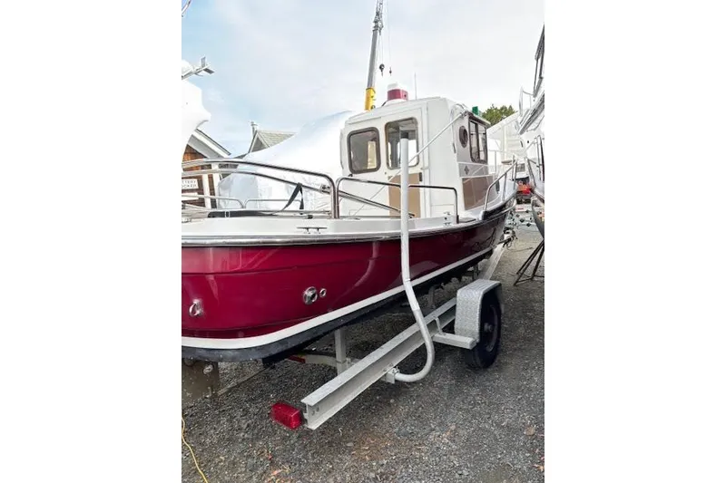 Slide: The Image of 2009 Ranger Tugs R21-EC boat on trailer, red hull, parked outdoors. - 2