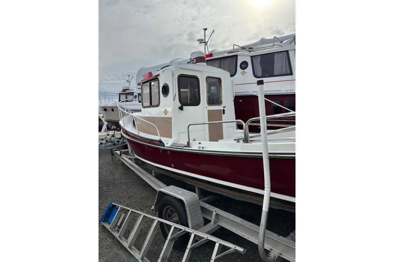 Slide: The Image of 2009 Ranger Tugs R21-EC boat on trailer, red and white exterior, parked outdoors. - 4