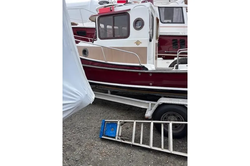 Slide: The Image of 2009 Ranger Tugs R21-EC boat on trailer, red and white exterior, parked outdoors. - 5