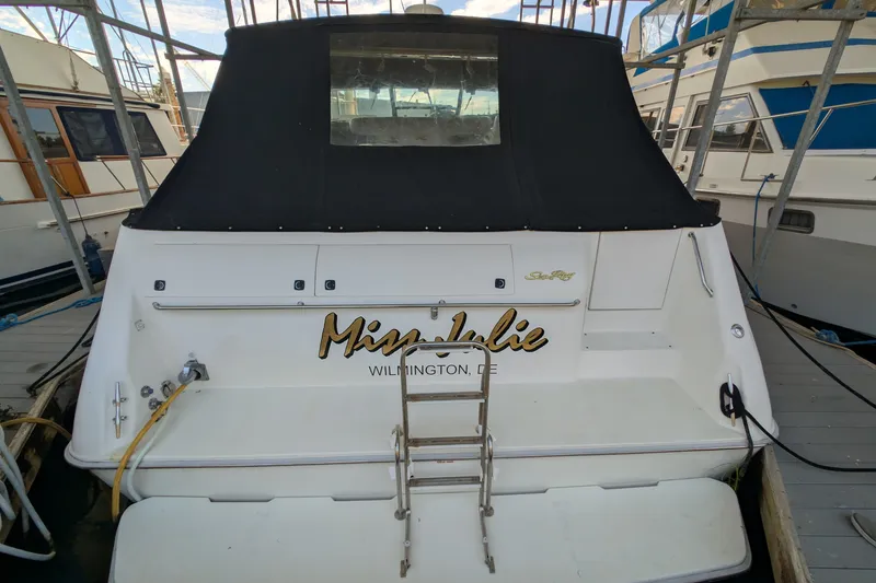 Slide: The Image of 1994 Sea Ray 500 Sundancer docked, rear view with black cover and ladder. - 2
