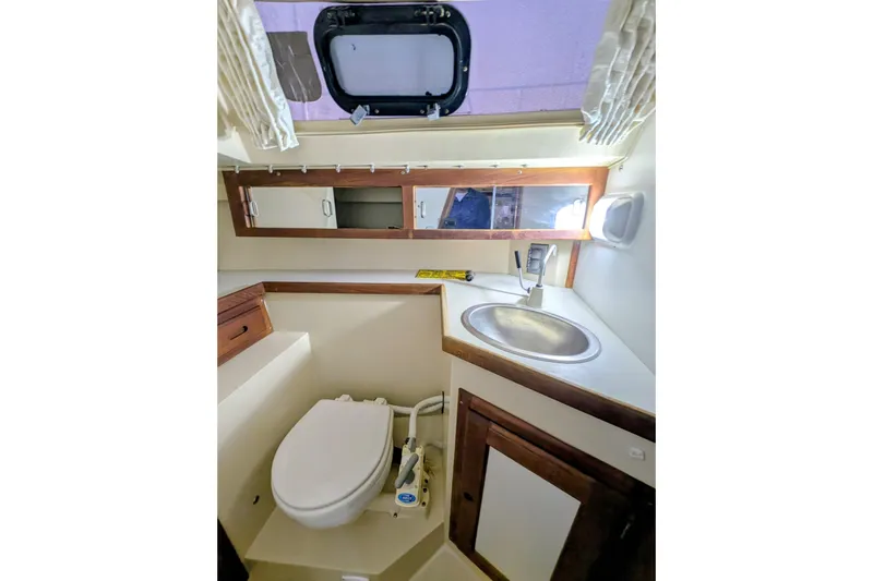 Slide: The Image of 1990 Catalina Capri 26 boat bathroom with toilet, sink, and storage cabinets. - 7