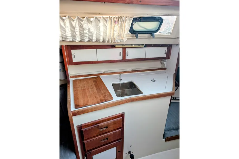 Slide: The Image of 1990 Catalina Capri 26 interior galley with sink, wooden countertop, and storage cabinets. - 9