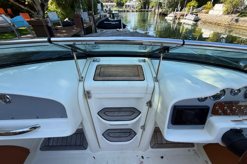 Slide: The Image of 2018 Chris-Craft Capri 27 boat dashboard with controls and storage compartments. - 29