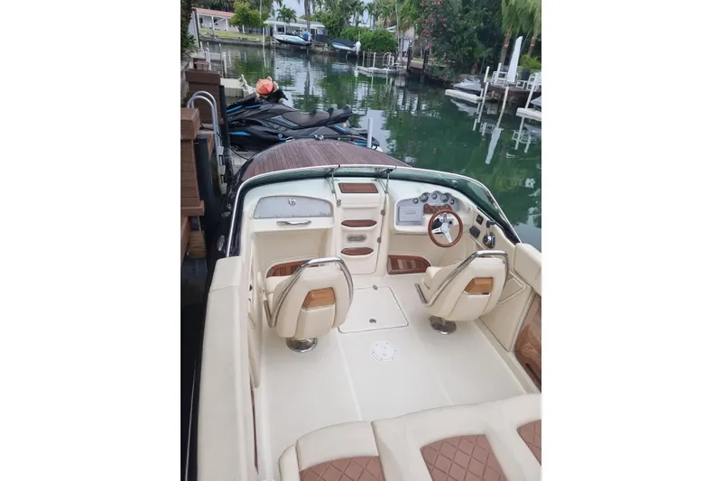 Slide: The Image of 2018 Chris-Craft Capri 27 boat on water, surrounded by lush greenery. - 3