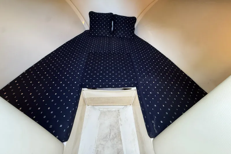 Slide: The Image of 2018 Chris-Craft Capri 27 cabin interior with patterned bedding and pillows. - 33