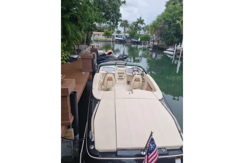 Slide: The Image of 2018 Chris-Craft Capri 27 boat on calm water, surrounded by lush greenery. - 4