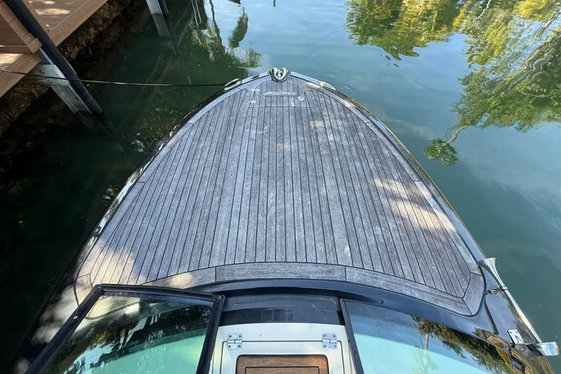 Slide: The Image of 2018 Chris-Craft Capri 27 boat deck with wooden finish, docked on calm water. - 44