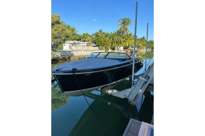 Slide: The Image of 2018 Chris-Craft Capri 27 boat cruising on a calm waterway, surrounded by lush greenery. - 5