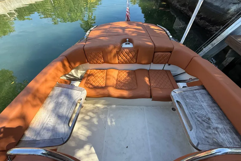 Slide: The Image of 2018 Chris-Craft Capri 27 boat interior with tan leather seating and wooden tables. - 54