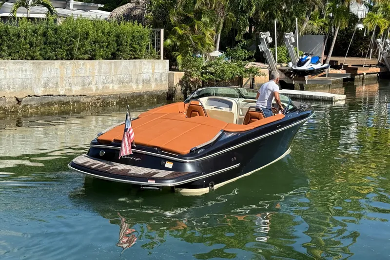 Slide: The Image of 2018 Chris-Craft Capri 27 boat on water, featuring sleek design and American flag. - 7