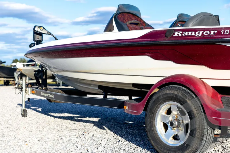 Slide: The Image of 2002 Ranger 185 VS boat on trailer, parked on gravel under blue sky. - 21