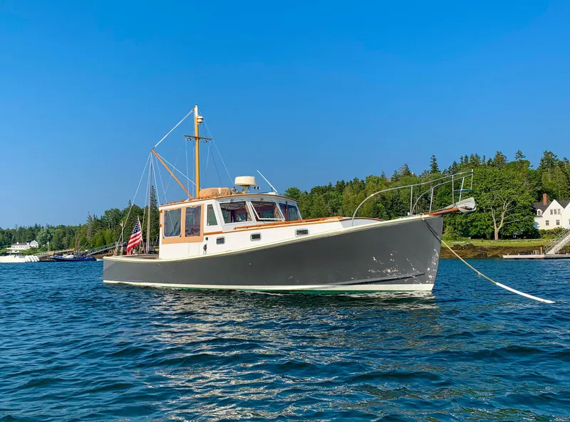 The Image of Classic 2003 John Williams Stanley 38 boat on serene water with lush green shoreline. - 0