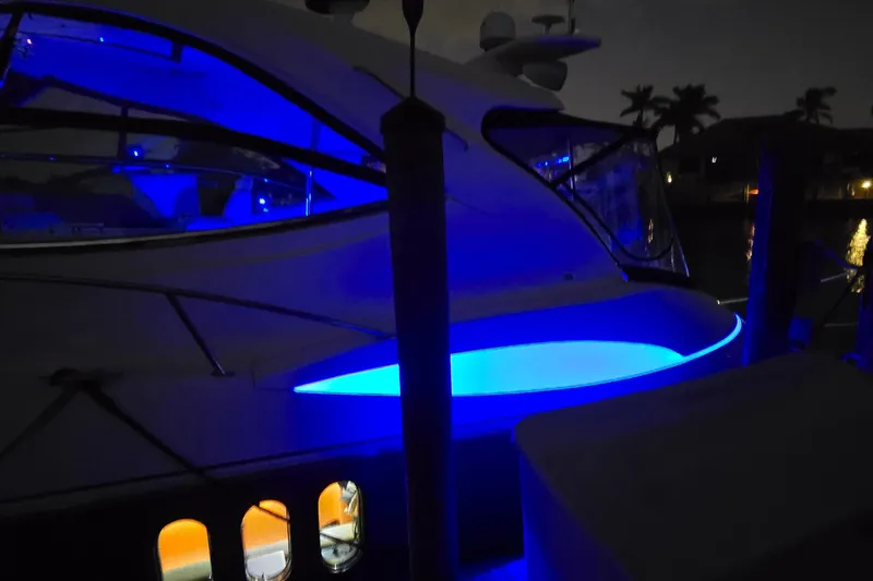 Slide: The Image of 2006 Cruisers Yachts 520 Express with blue LED lights at night, docked near palm trees. - 14