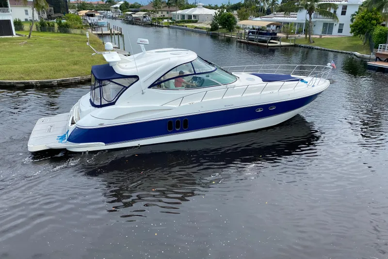 Slide: The Image of 2006 Cruisers Yachts 520 Express navigating a serene canal, surrounded by lush greenery. - 1