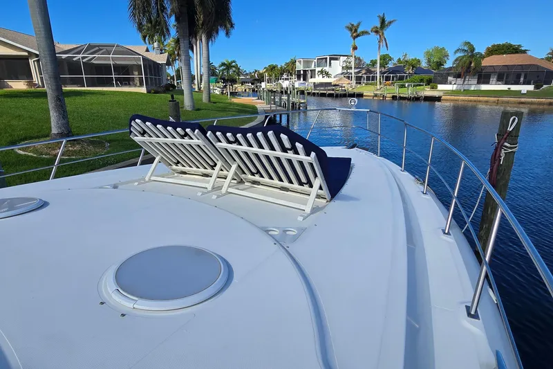 Slide: The Image of 2006 Cruisers Yachts 520 Express bow with anchor and spotlight, docked near a fence. - 44