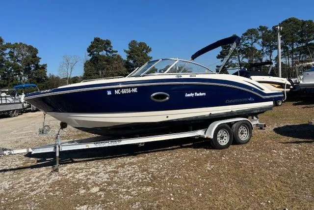 The Image of 2018 Chaparral 230 Suncoast boat on trailer, parked outdoors, with trees in background. - 0
