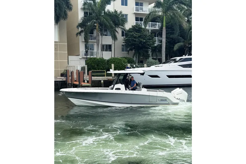 The Image of 2024 Boston Whaler 280 Outrage cruising near waterfront buildings and palm trees. - 0