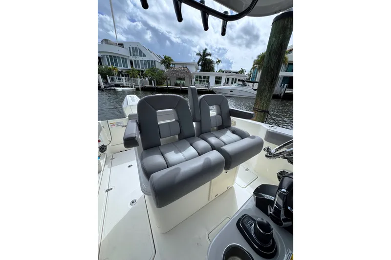 Slide: The Image of 2024 Boston Whaler 280 Outrage boat interior with gray seating and waterfront view. - 10