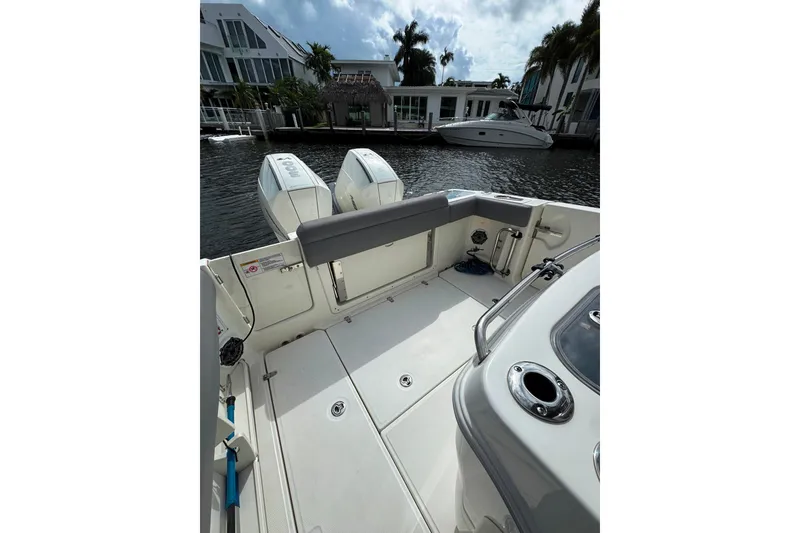 Slide: The Image of 2024 Boston Whaler 280 Outrage boat deck with dual engines, docked by waterfront homes. - 11
