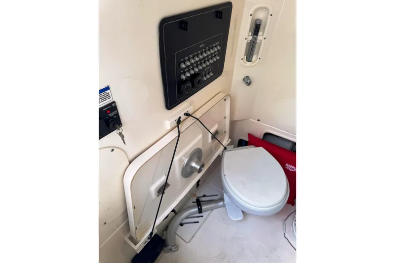 Slide: The Image of 2024 Boston Whaler 280 Outrage interior with control panel and marine toilet. - 16