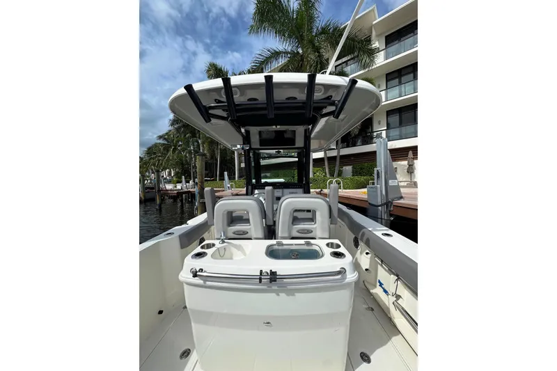 Slide: The Image of 2024 Boston Whaler 280 Outrage boat interior with seating and console, docked near palm trees. - 30