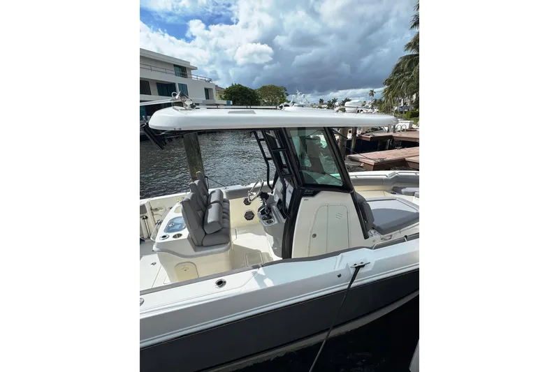 Slide: The Image of 2024 Boston Whaler 280 Outrage boat docked by waterfront, showcasing sleek design and seating. - 6